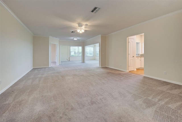 empty room featuring ceiling fan, light colored carpet, and ornamental molding