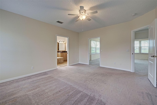 interior space with ensuite bath, ceiling fan, light colored carpet, and multiple windows