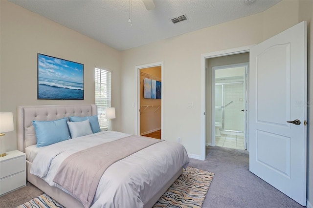 carpeted bedroom featuring ceiling fan, a walk in closet, a textured ceiling, and a closet