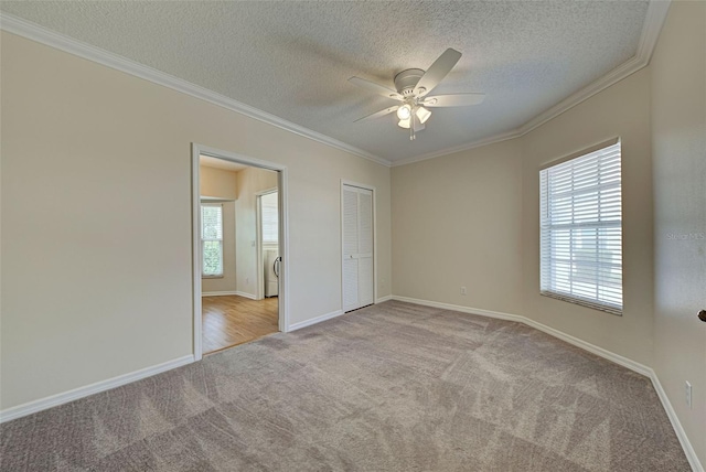 unfurnished bedroom with ceiling fan, crown molding, light colored carpet, and a textured ceiling