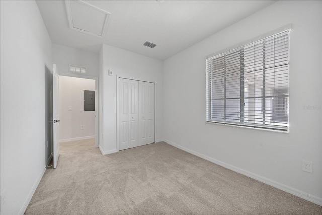 unfurnished bedroom featuring a closet, electric panel, and light colored carpet