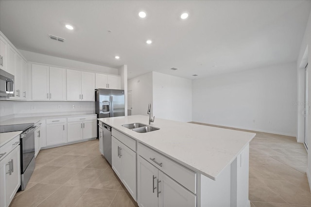 kitchen with appliances with stainless steel finishes, light tile patterned flooring, sink, an island with sink, and white cabinetry