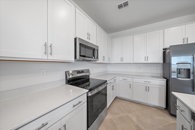 kitchen with white cabinetry, stainless steel appliances, and light tile patterned floors