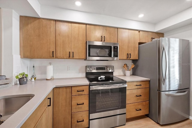 kitchen featuring appliances with stainless steel finishes, sink, and light wood-type flooring