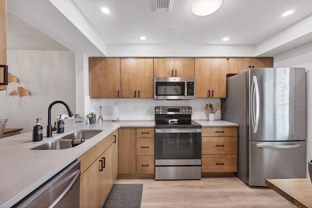 kitchen with sink, stainless steel appliances, and light hardwood / wood-style flooring