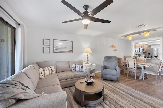 living room with sink, wood-type flooring, and ceiling fan