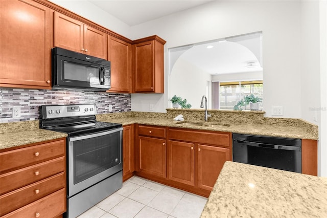 kitchen featuring sink, light tile patterned floors, light stone countertops, decorative backsplash, and black appliances