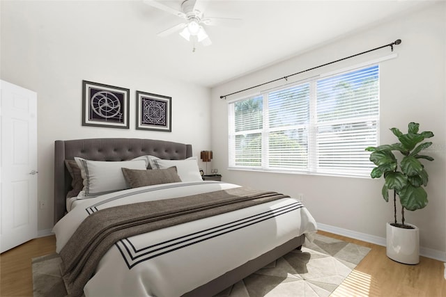 bedroom featuring ceiling fan, multiple windows, and light hardwood / wood-style flooring