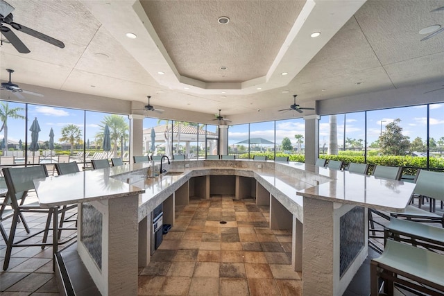 kitchen with a kitchen breakfast bar, a large island, light stone countertops, and sink