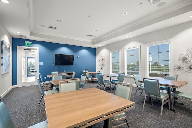 dining area featuring crown molding, a raised ceiling, and dark colored carpet