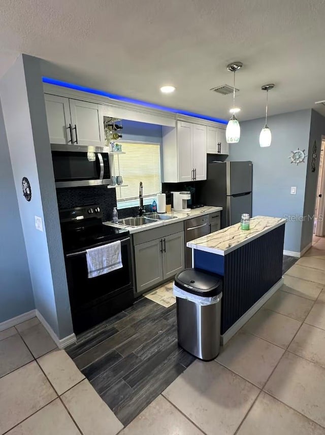 kitchen featuring hanging light fixtures, stainless steel appliances, sink, a center island, and tile patterned flooring