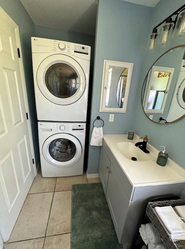 clothes washing area with sink, stacked washer / dryer, and light tile patterned flooring