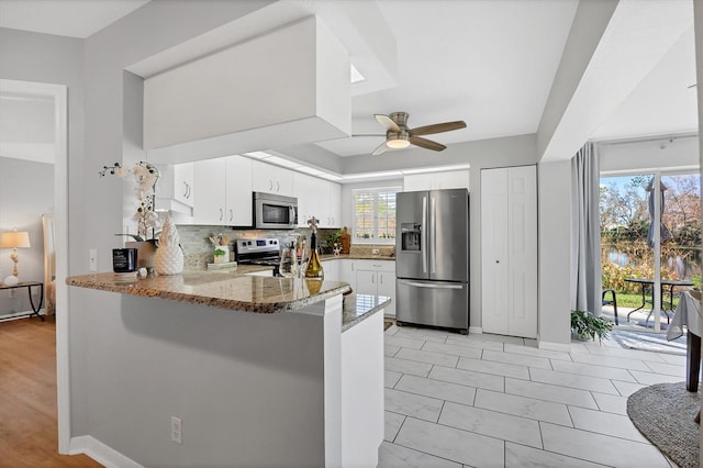 kitchen featuring kitchen peninsula, white cabinetry, plenty of natural light, and stainless steel appliances