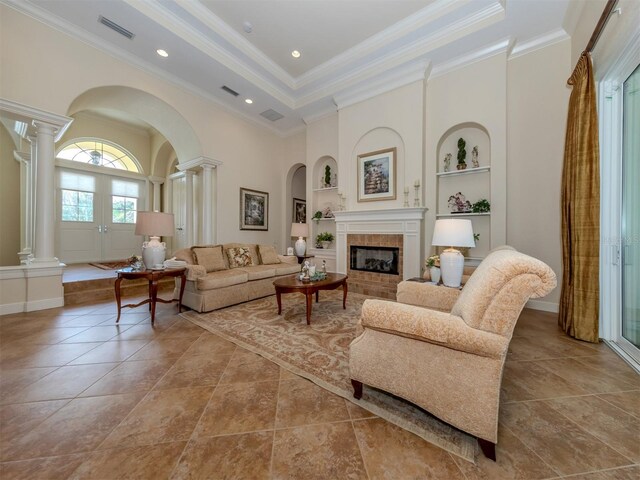 tiled living room featuring french doors, ornate columns, ornamental molding, built in features, and a fireplace