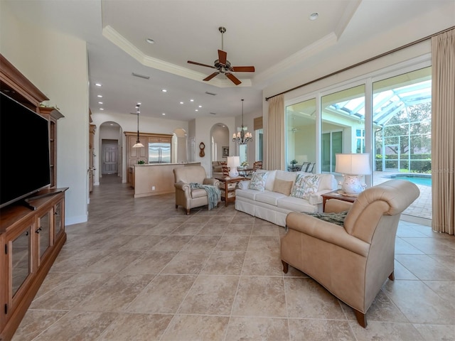 living room featuring crown molding, a tray ceiling, and ceiling fan with notable chandelier