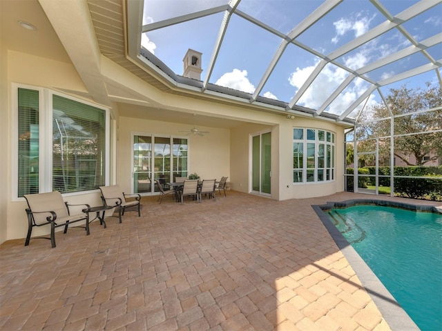 view of swimming pool featuring a patio area, ceiling fan, and glass enclosure