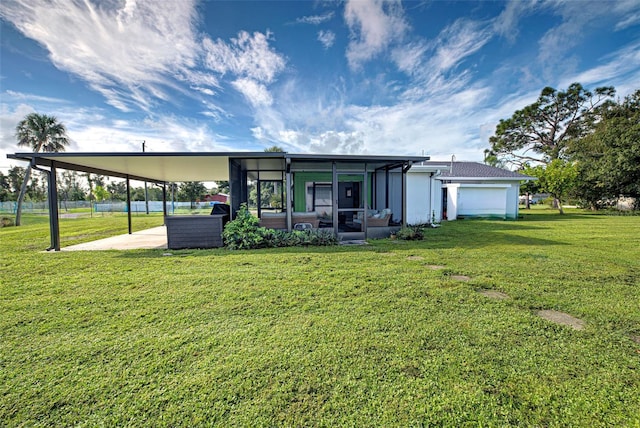 rear view of property with a carport, a lawn, and a garage