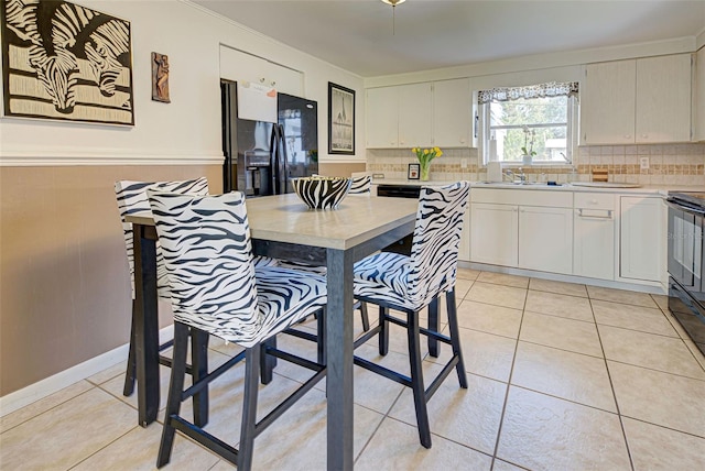 kitchen with black appliances, light tile patterned flooring, white cabinets, and tasteful backsplash