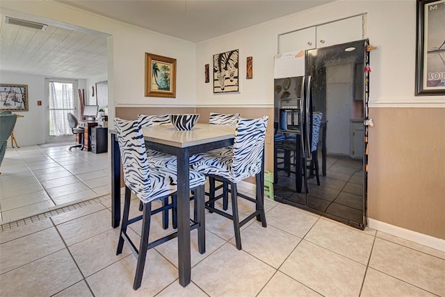 dining area with light tile patterned flooring, visible vents, and wainscoting