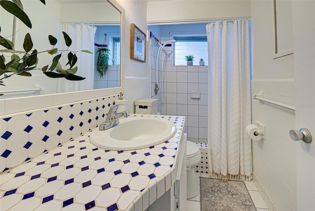bathroom with vanity, toilet, tile patterned floors, a shower with shower curtain, and tile walls