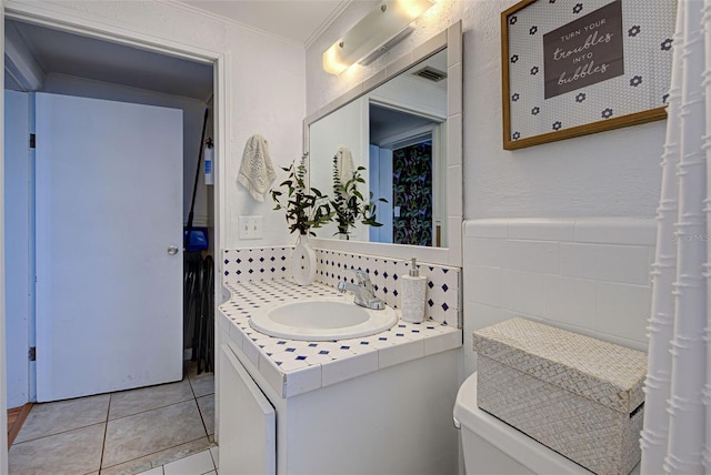 half bathroom with vanity, toilet, tile patterned floors, tile walls, and ornamental molding
