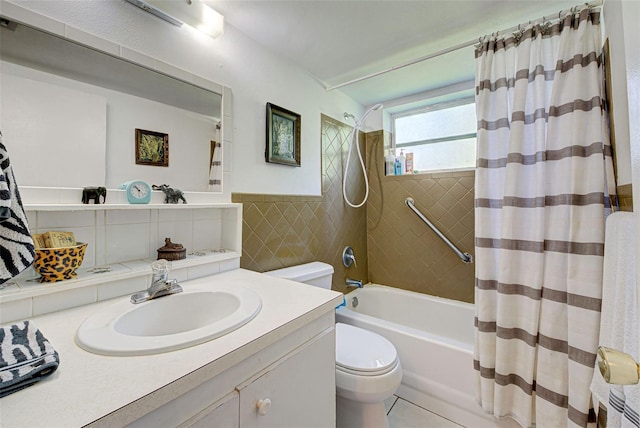 full bath featuring vanity, shower / tub combo with curtain, toilet, a wainscoted wall, and tile walls