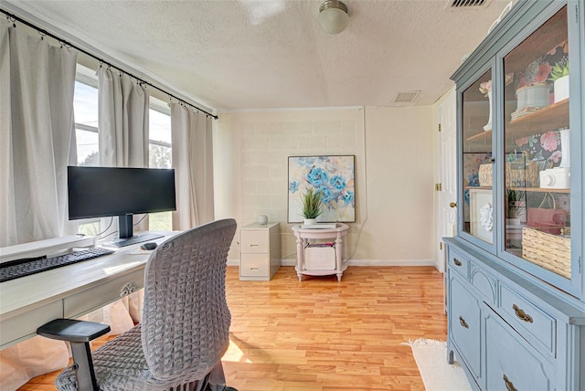 home office with a textured ceiling and light hardwood / wood-style floors