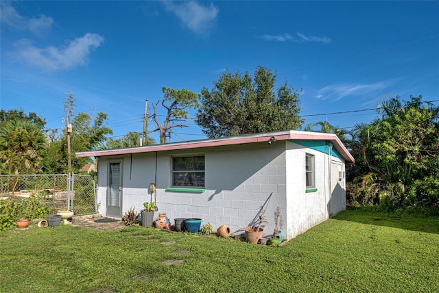 view of property exterior with a lawn, concrete block siding, and fence