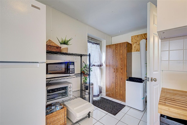 kitchen featuring white fridge, wood walls, and light tile patterned floors