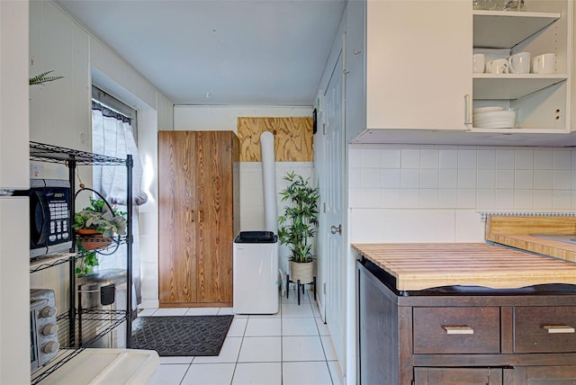 kitchen with light tile patterned floors, dark brown cabinets, and backsplash