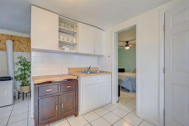 kitchen with a sink, light countertops, light tile patterned floors, and open shelves