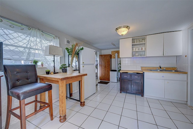 kitchen featuring backsplash, open shelves, a sink, white cabinets, and freestanding refrigerator