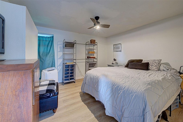 bedroom with a wall unit AC, a ceiling fan, and wood finished floors