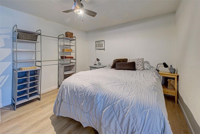 bedroom with a wall mounted air conditioner, wood-type flooring, and ceiling fan