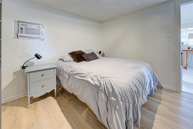 bedroom with a wall mounted AC and light wood-type flooring