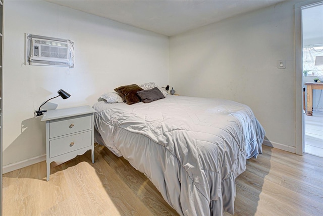 bedroom featuring baseboards, a wall mounted AC, and wood finished floors