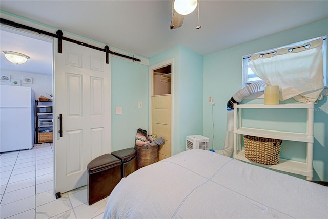 bedroom with a barn door, ceiling fan, and white refrigerator