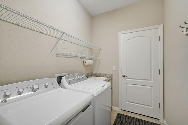 laundry area featuring sink, light tile patterned floors, and washing machine and clothes dryer