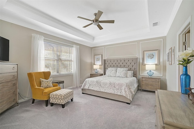 bedroom featuring crown molding, ceiling fan, a tray ceiling, and light carpet