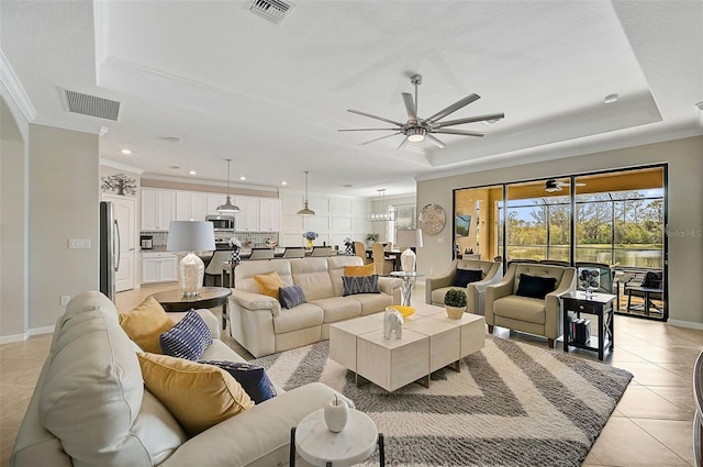 tiled living room with a raised ceiling, ornamental molding, and ceiling fan