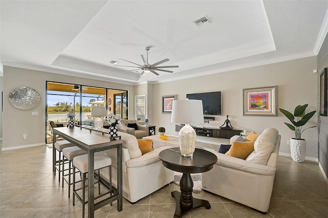 tiled living room with crown molding, ceiling fan, and a tray ceiling