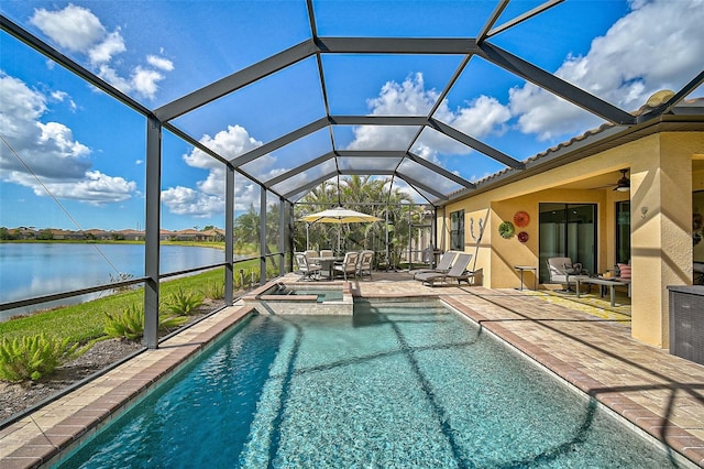 view of swimming pool featuring glass enclosure, a patio, a water view, a ceiling fan, and a pool with connected hot tub