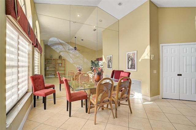 tiled dining space with ceiling fan and high vaulted ceiling