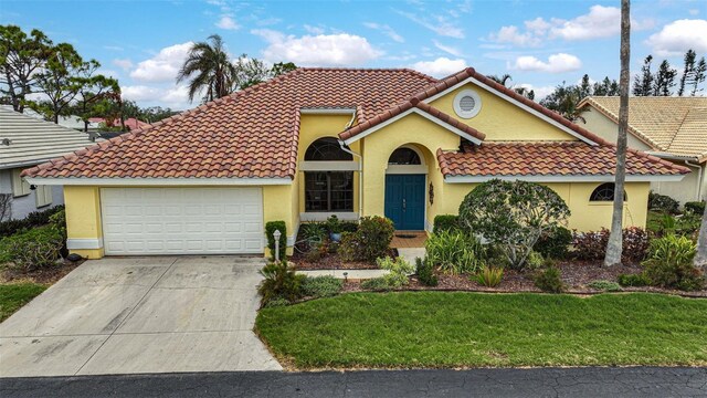 mediterranean / spanish home featuring a front lawn and a garage