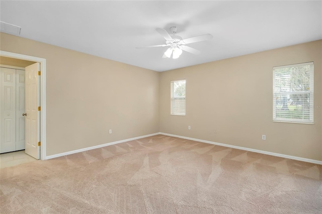 spare room featuring a wealth of natural light, ceiling fan, and light colored carpet