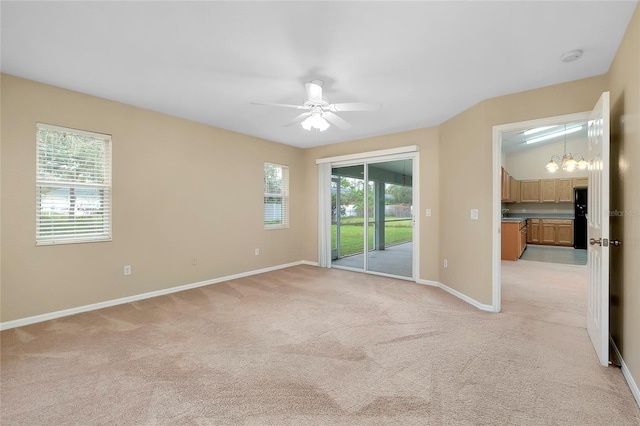 carpeted empty room with ceiling fan with notable chandelier and lofted ceiling