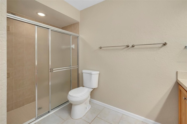 bathroom with tile patterned floors, vanity, toilet, and a shower with door