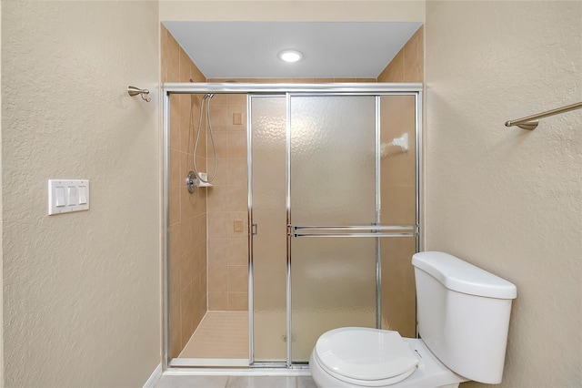 bathroom featuring toilet and a shower with door