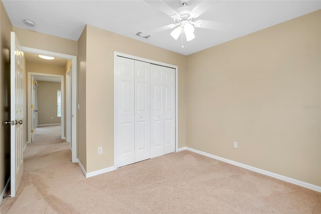 unfurnished bedroom with light carpet, a closet, and ceiling fan