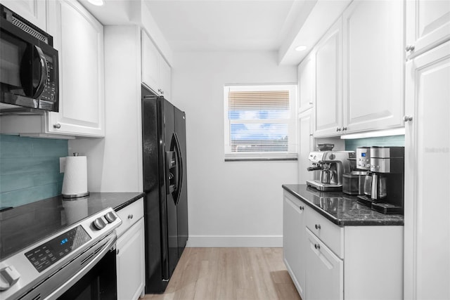 kitchen featuring white cabinets, light hardwood / wood-style flooring, black appliances, and dark stone counters